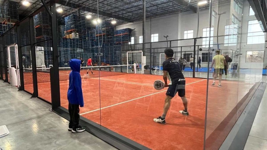 Players on a glass-walled padel court inside the NorthPoint Padel warehouse in Westfield, Indiana